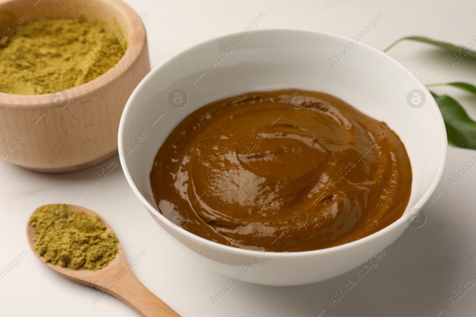 Photo of Bowls with henna powder and cream on white marble table, closeup. Natural hair coloring