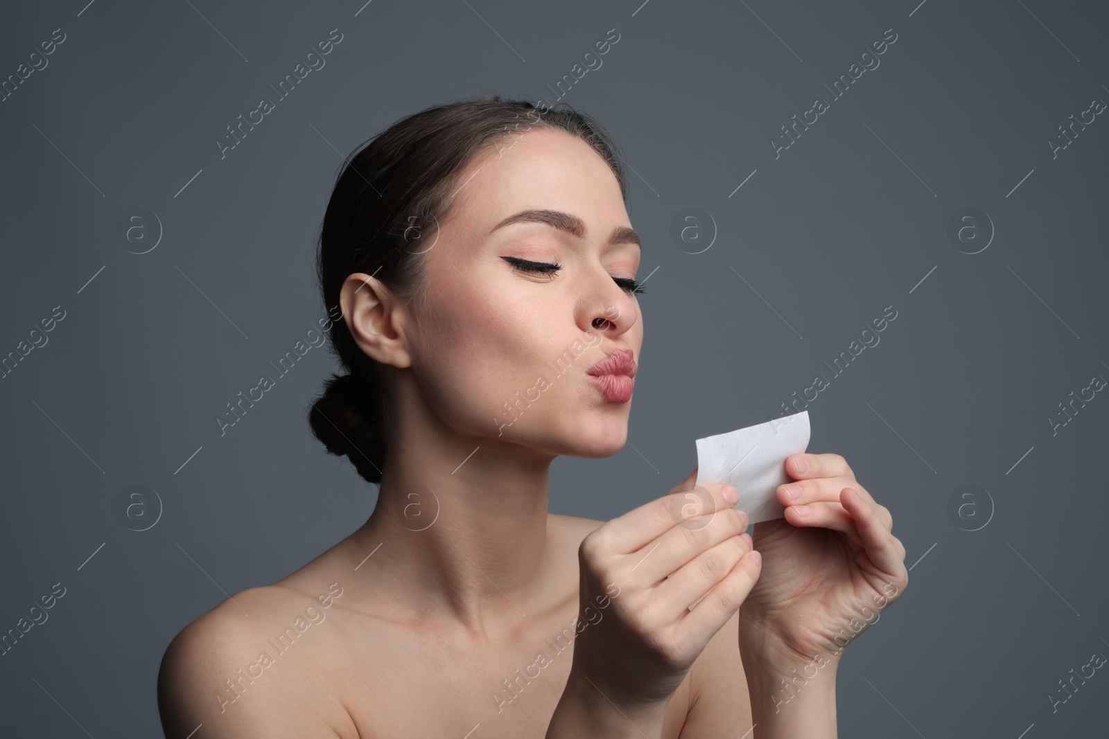 Photo of Beautiful woman with mattifying wipe on grey background