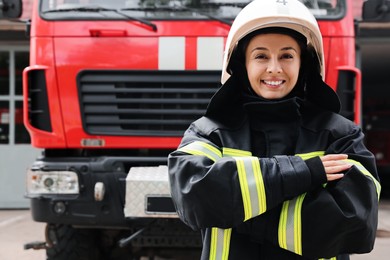Photo of Portrait of firefighter in uniform and helmet near fire truck outdoors