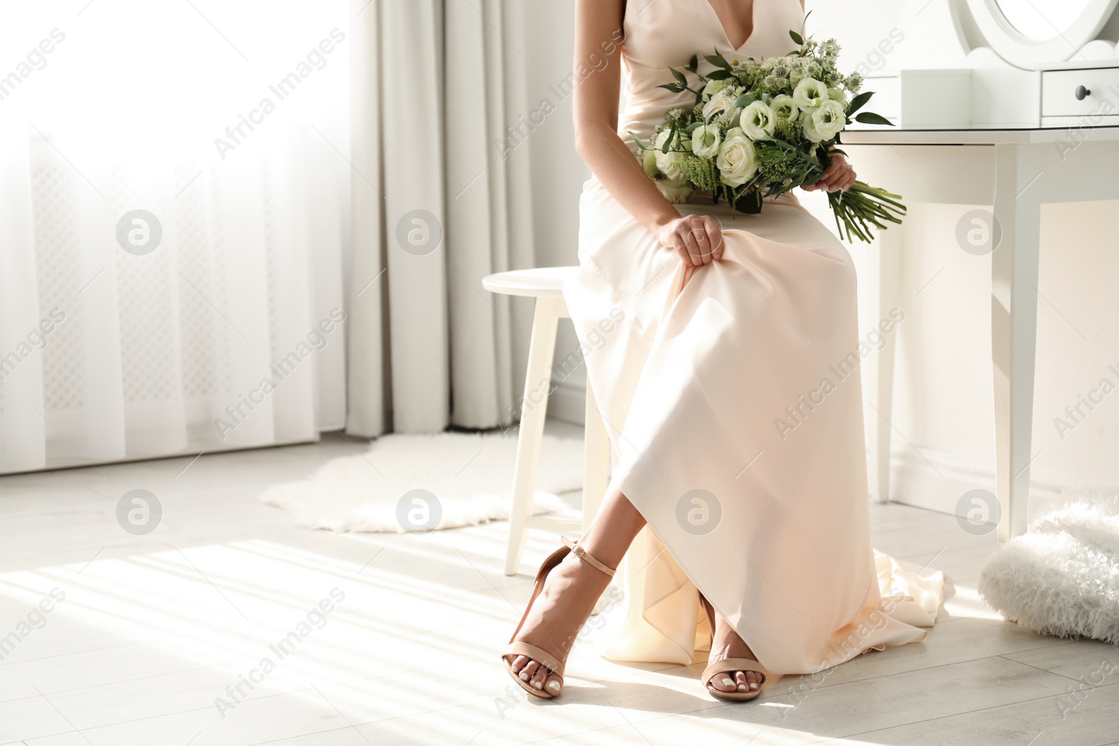 Photo of Young bride wearing wedding dress with beautiful bouquet near mirror indoors, closeup. Space for text