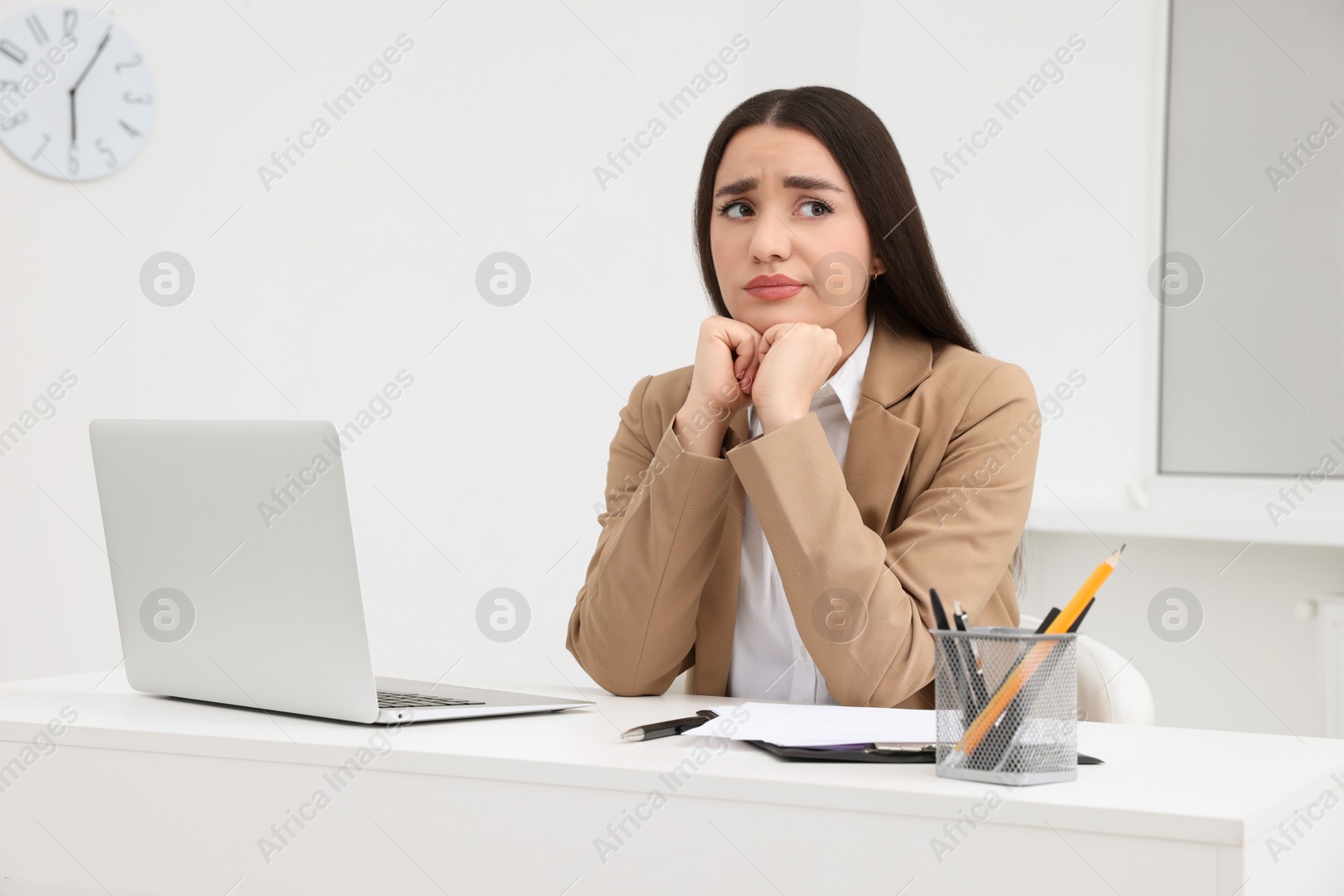 Photo of Unhappy young female intern at table in office