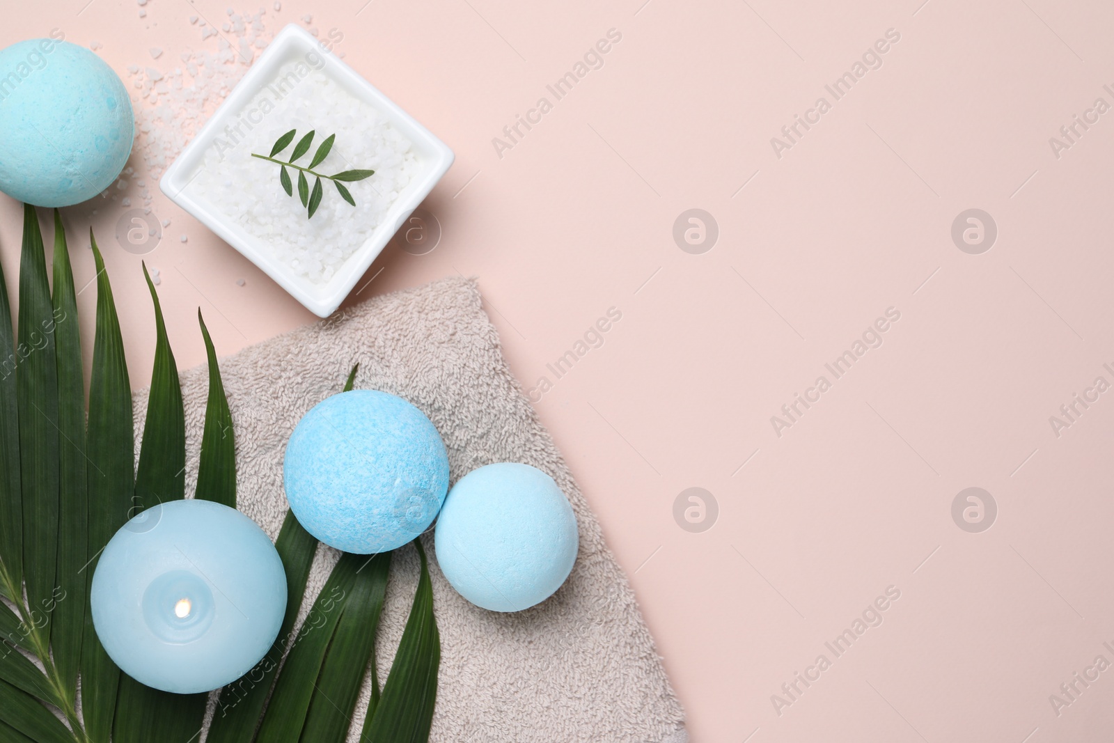 Photo of Bath bombs, green leaf, sea salt and burning candle on beige background, flat lay. Space for text