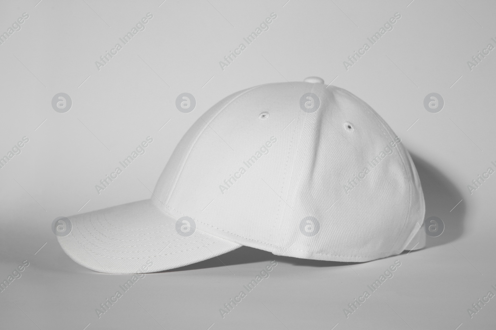 Photo of Stylish white baseball cap on light background