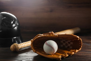 Photo of Baseball glove, bat, ball and batting helmet on wooden table, space for text
