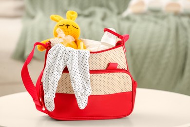 Photo of Mother's bag with baby's stuff on white table indoors