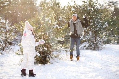 Photo of Father and daughter having snowball fight outdoors on winter day. Christmas vacation