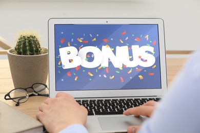 Bonus gaining. Man using laptop at table, closeup. Illustration of falling confetti and word on device screen