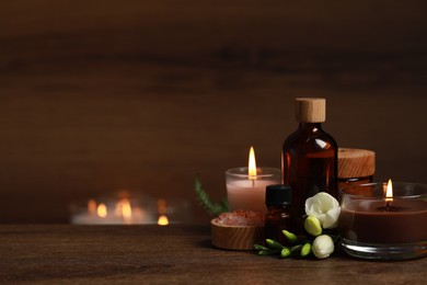 Photo of Beautiful spa composition with burning candles, different care products and flowers on wooden table. Space for text