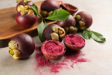 Purple mangosteen powder and fruits on light grey table