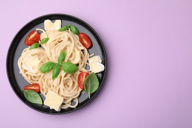 Photo of Delicious pasta with brie cheese, tomatoes and basil leaves on violet background, top view. Space for text