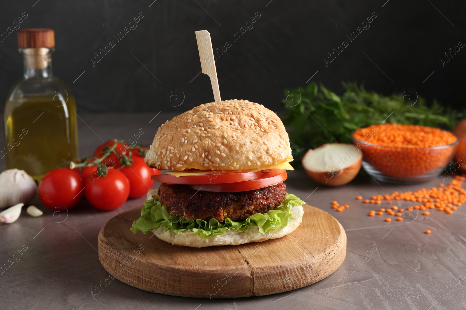 Photo of Board with delicious vegetarian burger on grey textured table