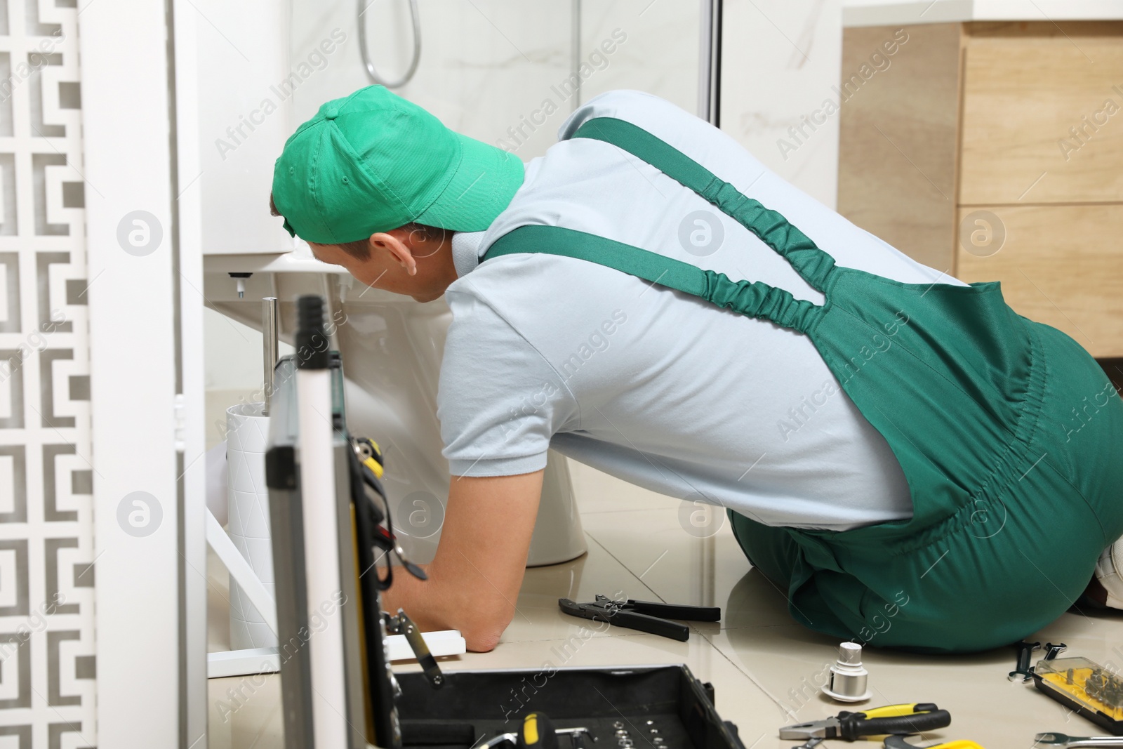 Photo of Professional plumber repairing toilet bowl in bathroom