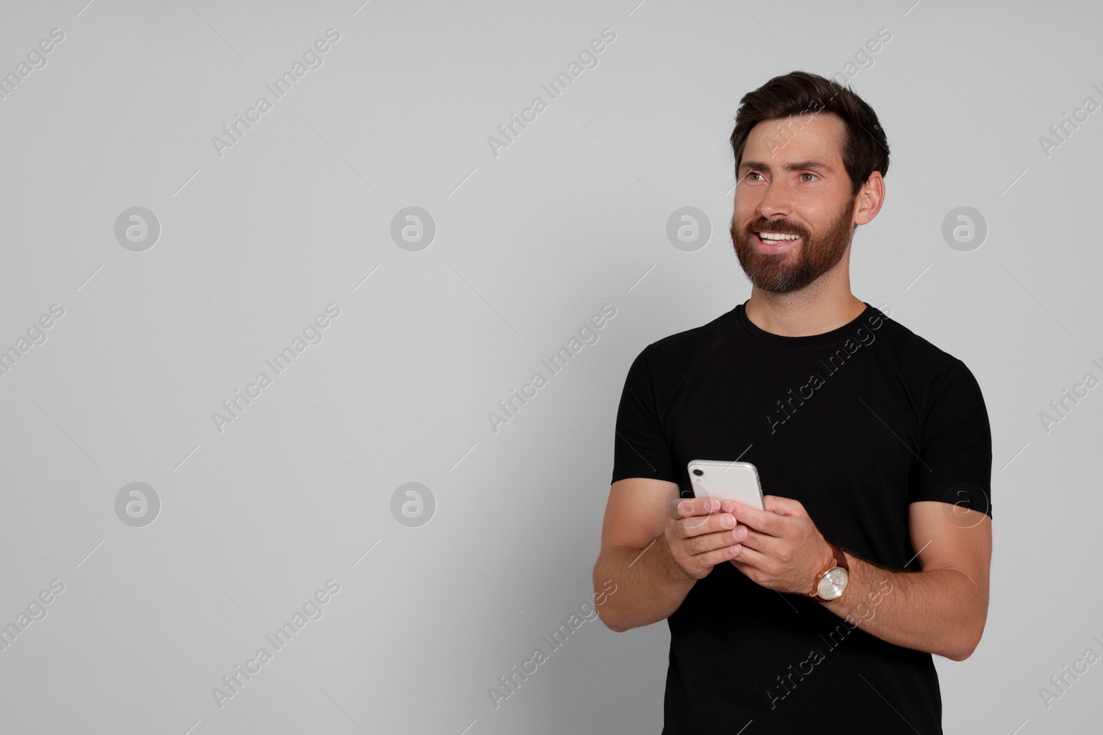 Photo of Happy man with smartphone on light background. Space for text