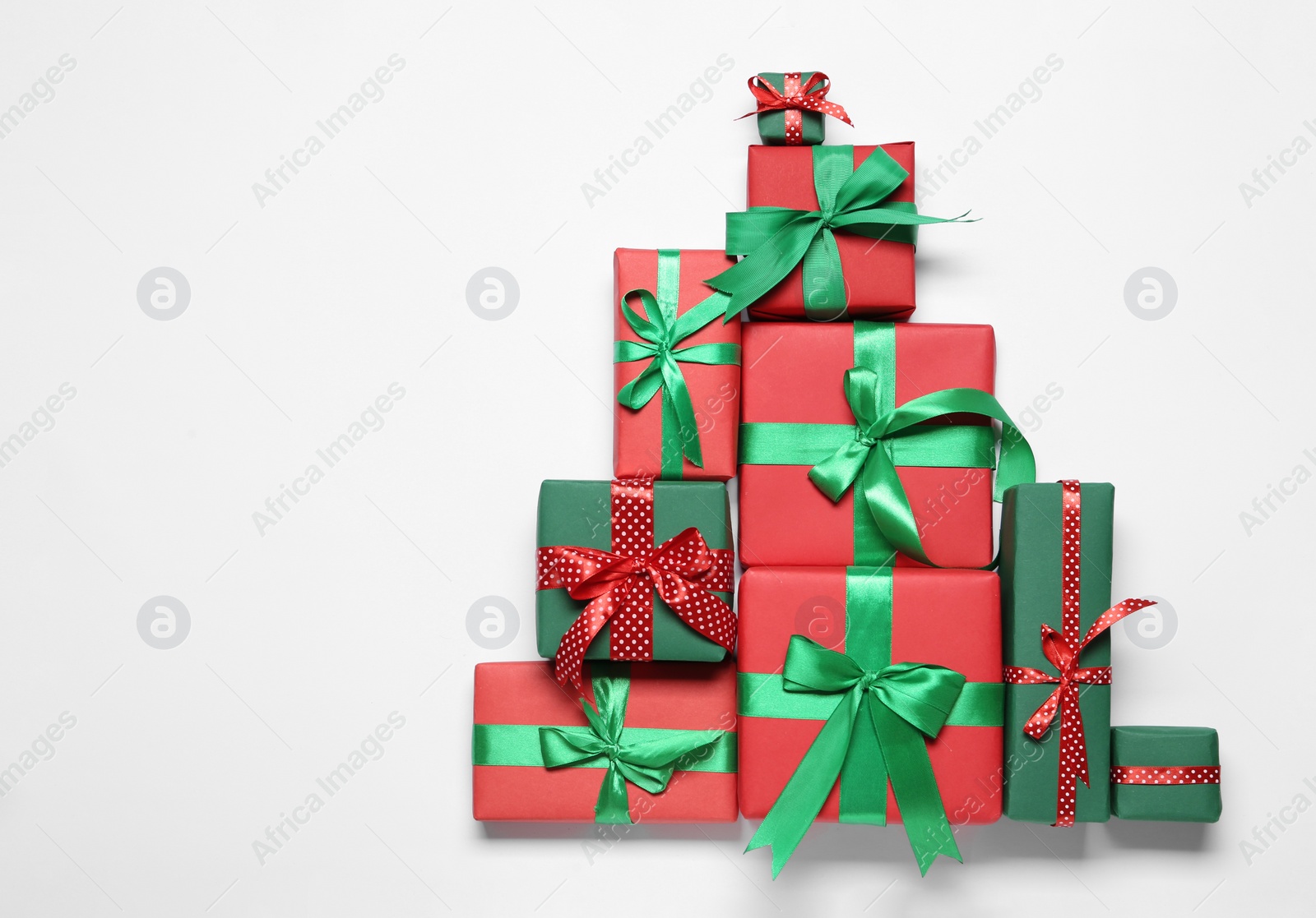 Photo of Christmas tree shape of gift boxes on white background, flat lay. Space for text