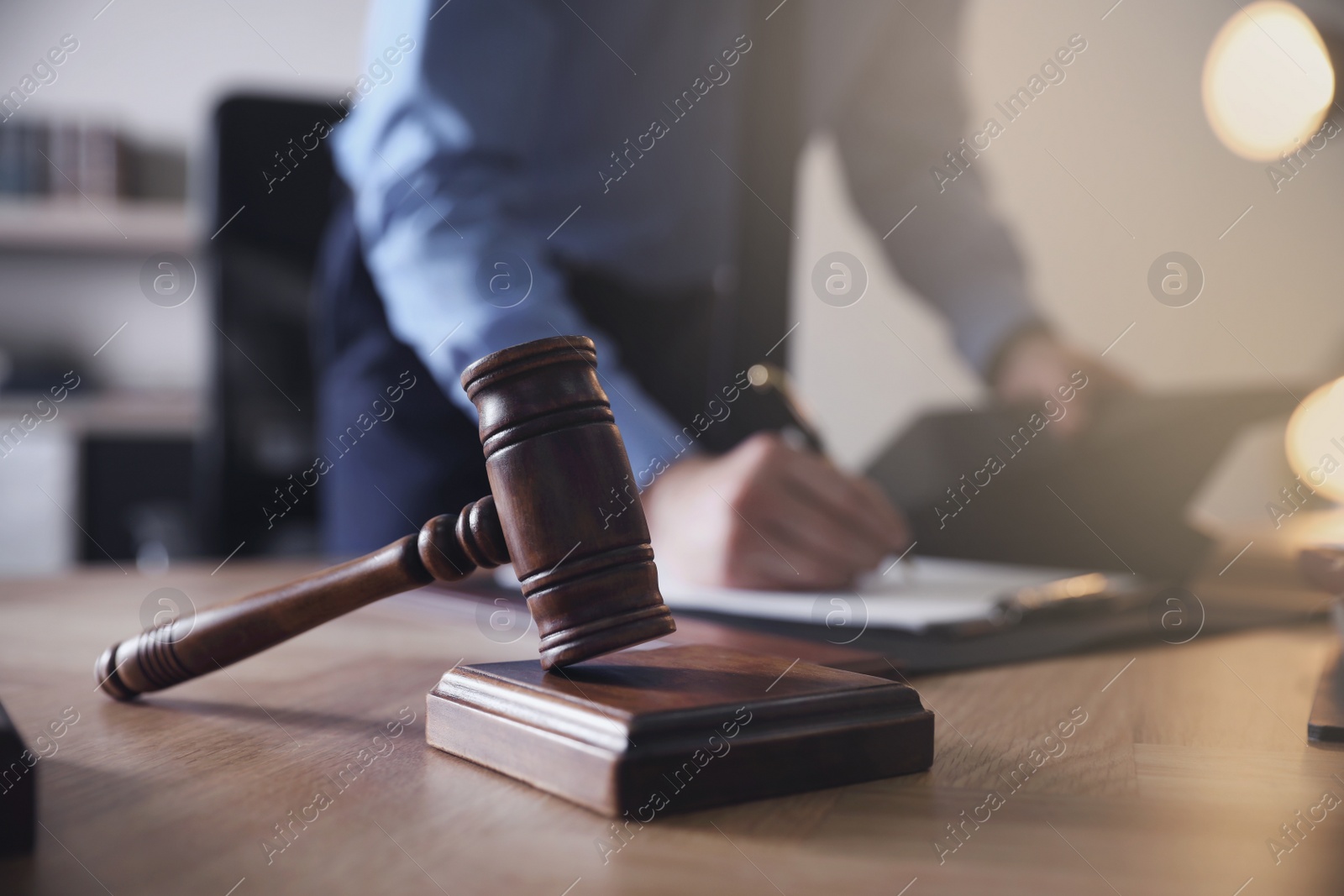 Photo of Male lawyer working at table in office, focus on gavel