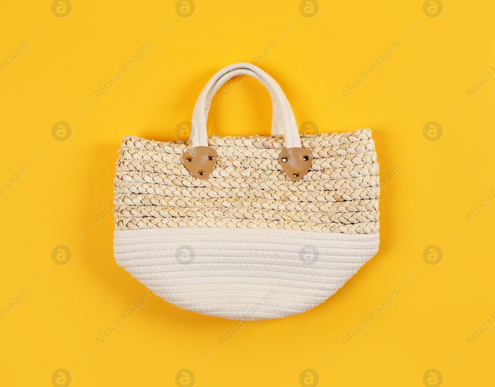 Photo of Stylish woman's straw bag on yellow background, top view
