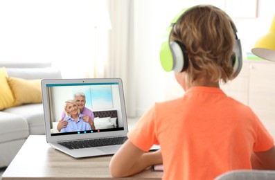 Image of Little boy talking with his grandparents via videocall application at home