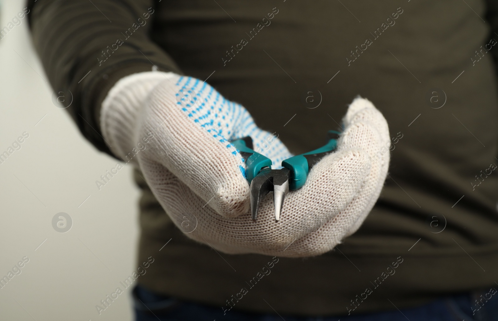 Photo of Man with bent nose pliers on light background, closeup