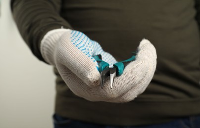 Photo of Man with bent nose pliers on light background, closeup