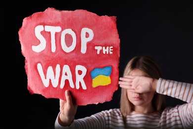 Photo of Woman holding poster with words Stop the War on black background