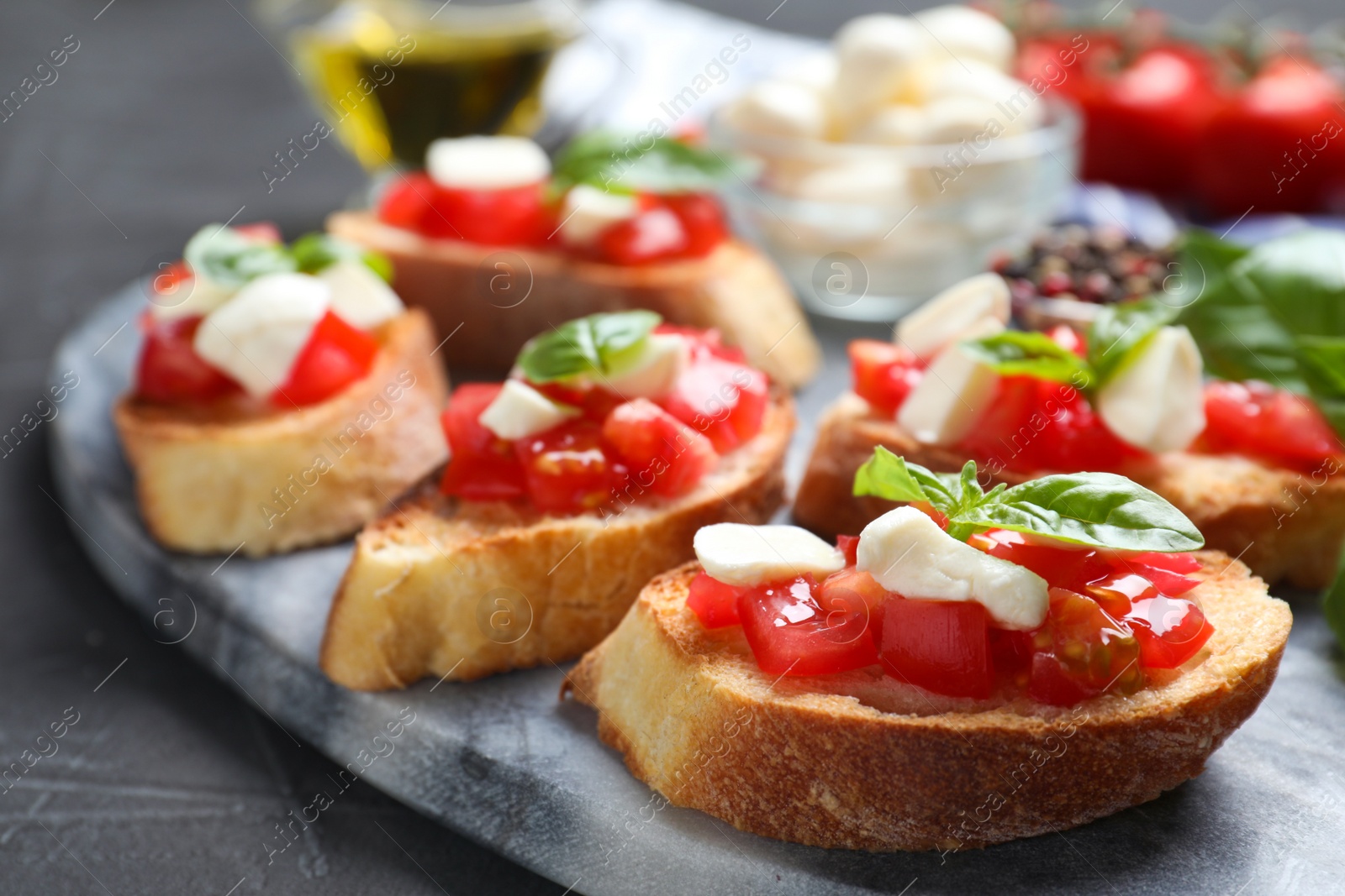 Photo of Delicious bruschettas with cheese and tomatoes on grey table, closeup