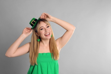 Photo of Happy woman in St Patrick's Day outfit on light grey background, space for text