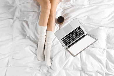 Top view of woman with laptop sitting on bed, closeup. Mockup for design