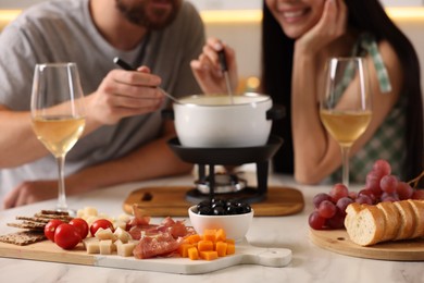 Photo of Couple enjoying fondue during romantic date, selective focus