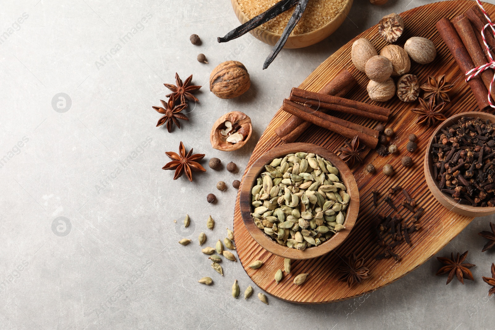 Photo of Different spices and nuts on light gray table, flat lay. Space for text