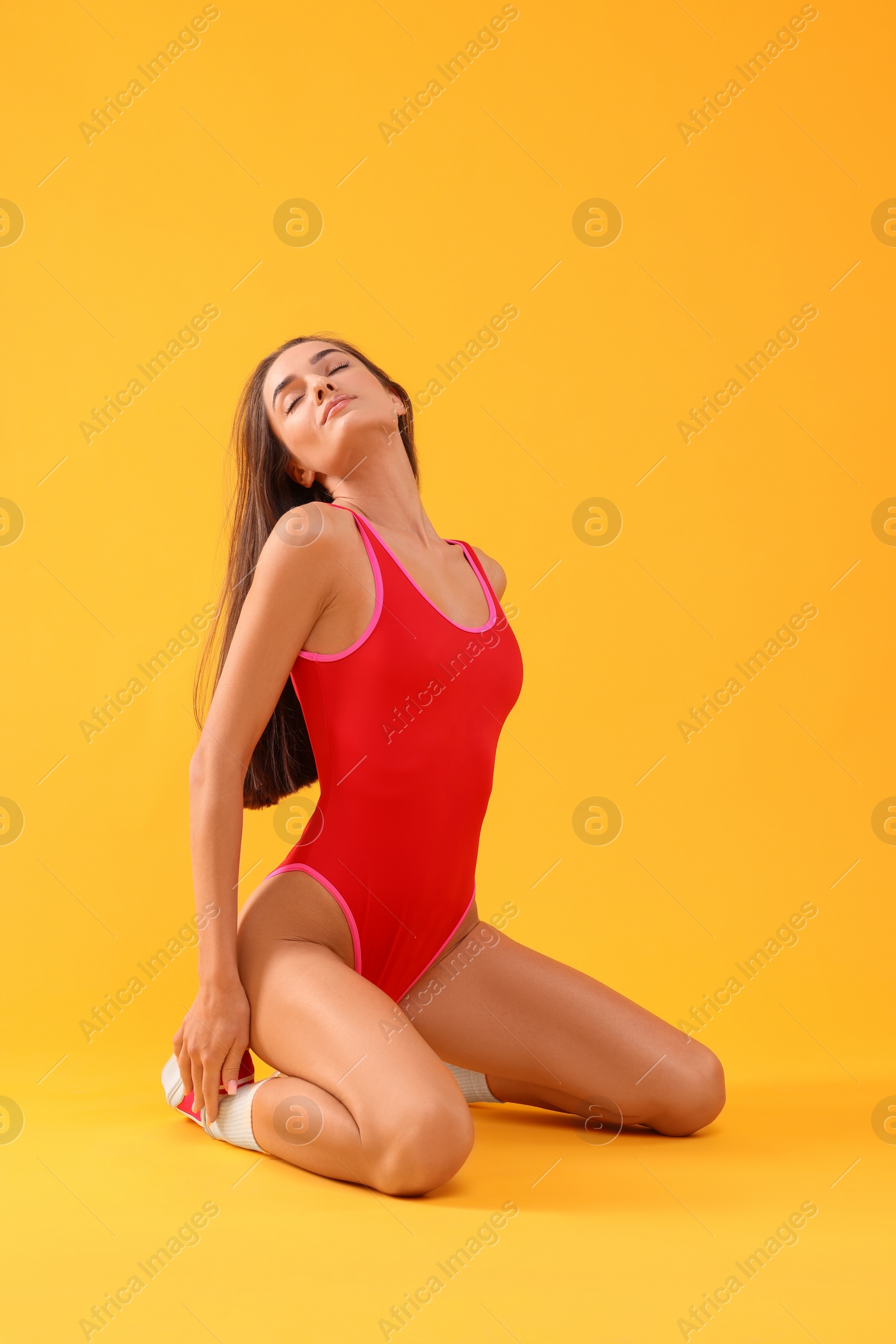 Photo of Young woman in stylish swimsuit on yellow background