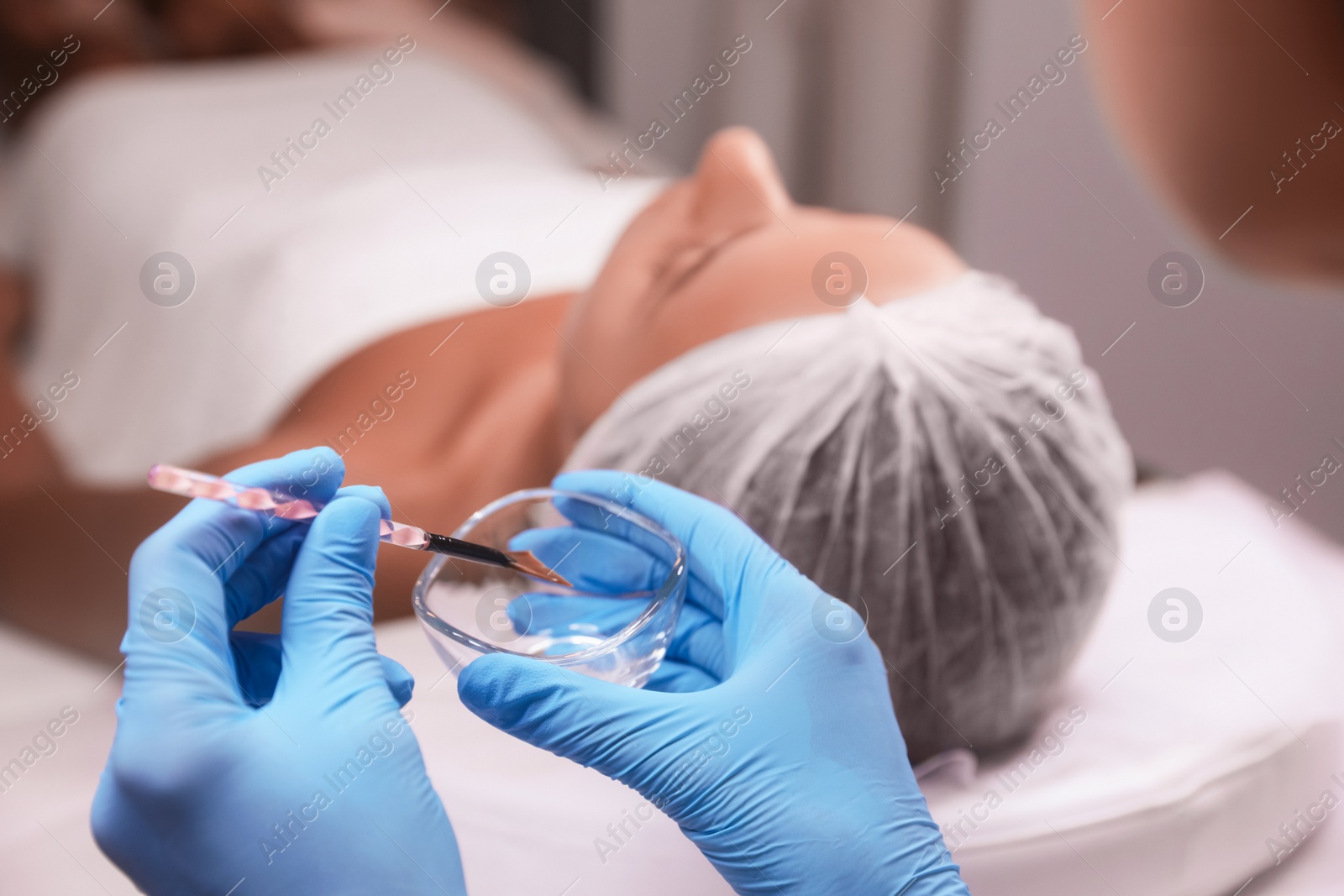 Photo of Cosmetologist with bowl and brush in salon. Peeling procedure