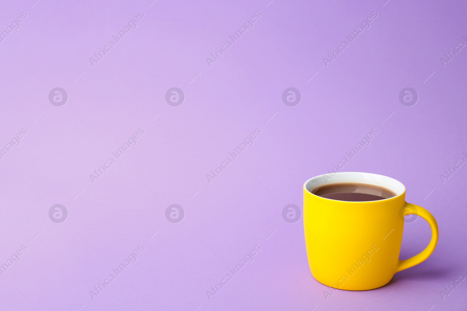 Photo of Yellow ceramic cup with hot aromatic coffee on color background