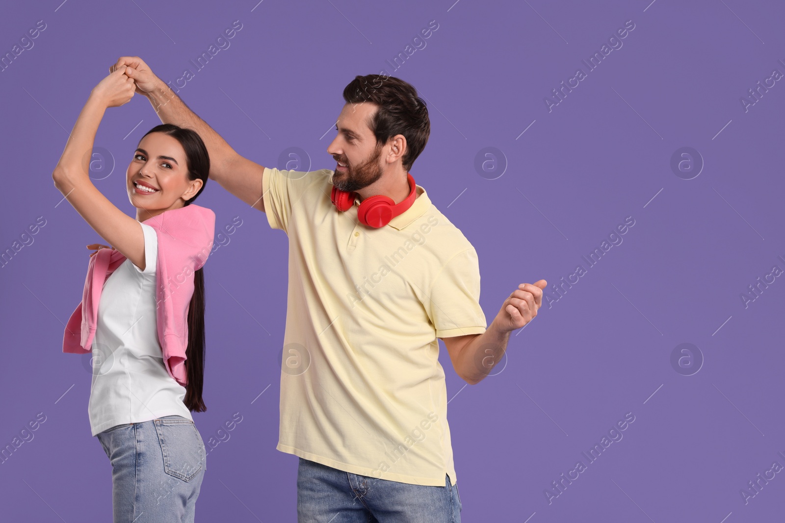 Photo of Happy couple dancing together on violet background, space for text