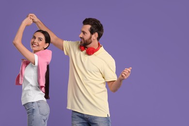 Photo of Happy couple dancing together on violet background, space for text