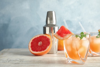 Glass of grapefruit cocktail served on table. Space for text