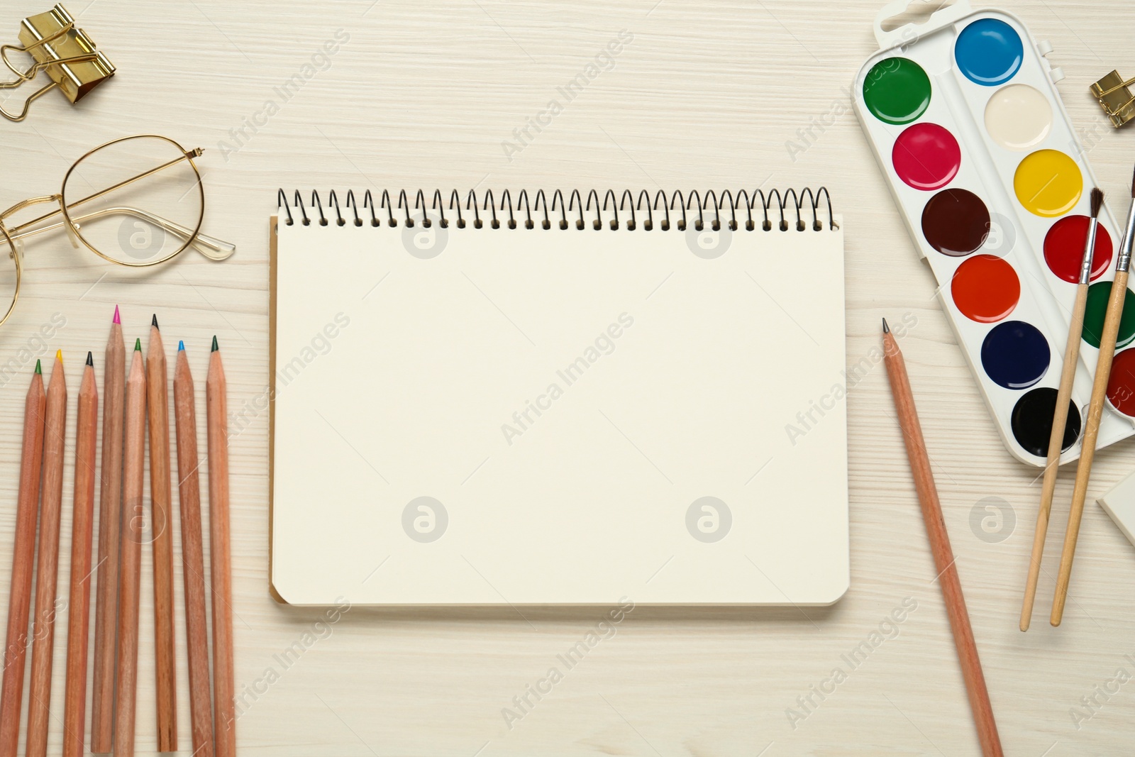 Photo of Flat lay composition with blank sketchbook on white wooden table. Space for text