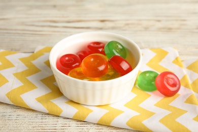 Bowl with delicious colorful candies on wooden table