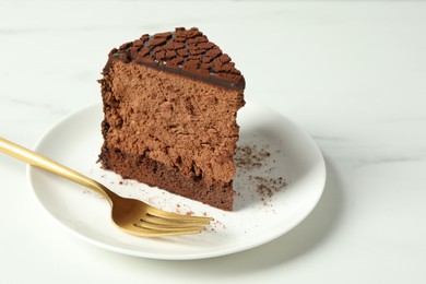 Photo of Piece of delicious chocolate truffle cake and fork on white marble table, closeup