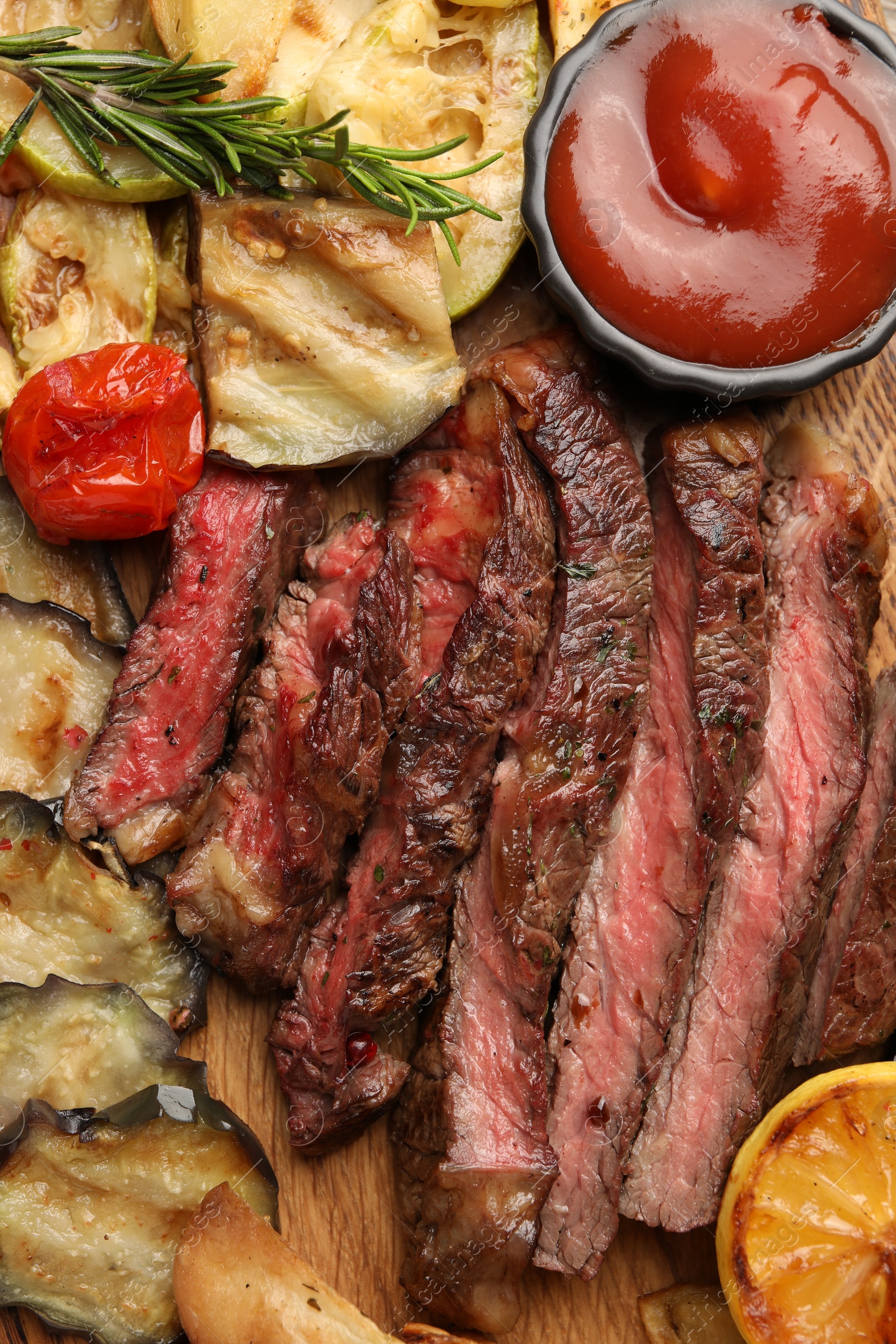 Photo of Delicious grilled beef with vegetables, spices and tomato sauce on table, top view