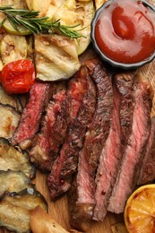 Photo of Delicious grilled beef with vegetables, spices and tomato sauce on table, top view