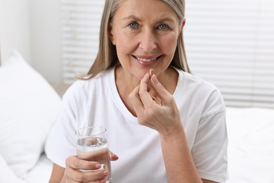 Beautiful woman taking vitamin pill at home