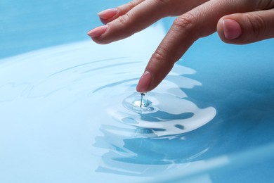 Woman touching clear water, closeup. Making ripples