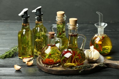 Photo of Cooking oil with different spices and herbs in bottles on grey wooden table