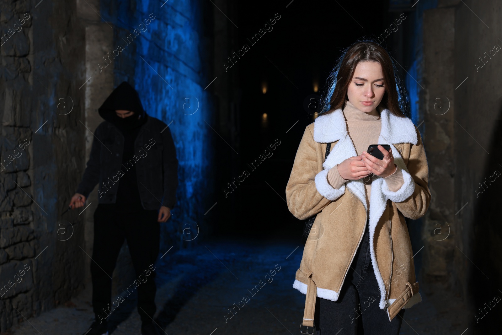 Photo of Man with knife stalking young woman in alley at night