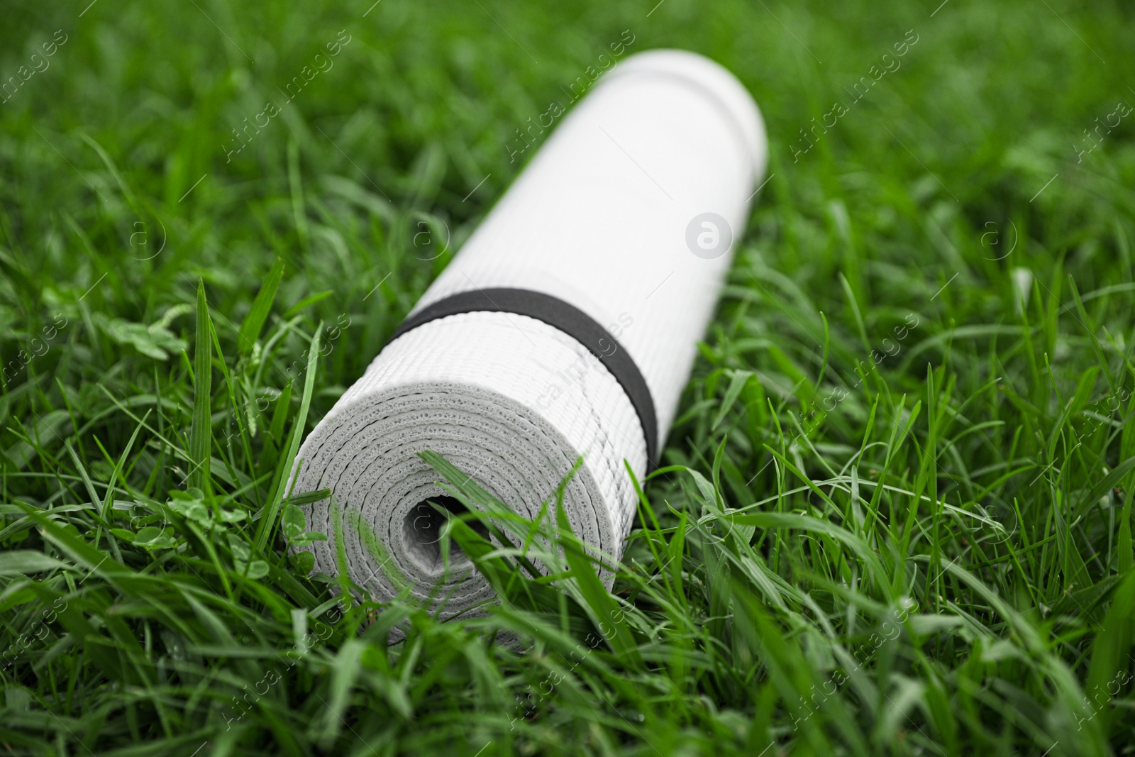 Photo of White karemat or fitness mat on green grass outdoors, closeup