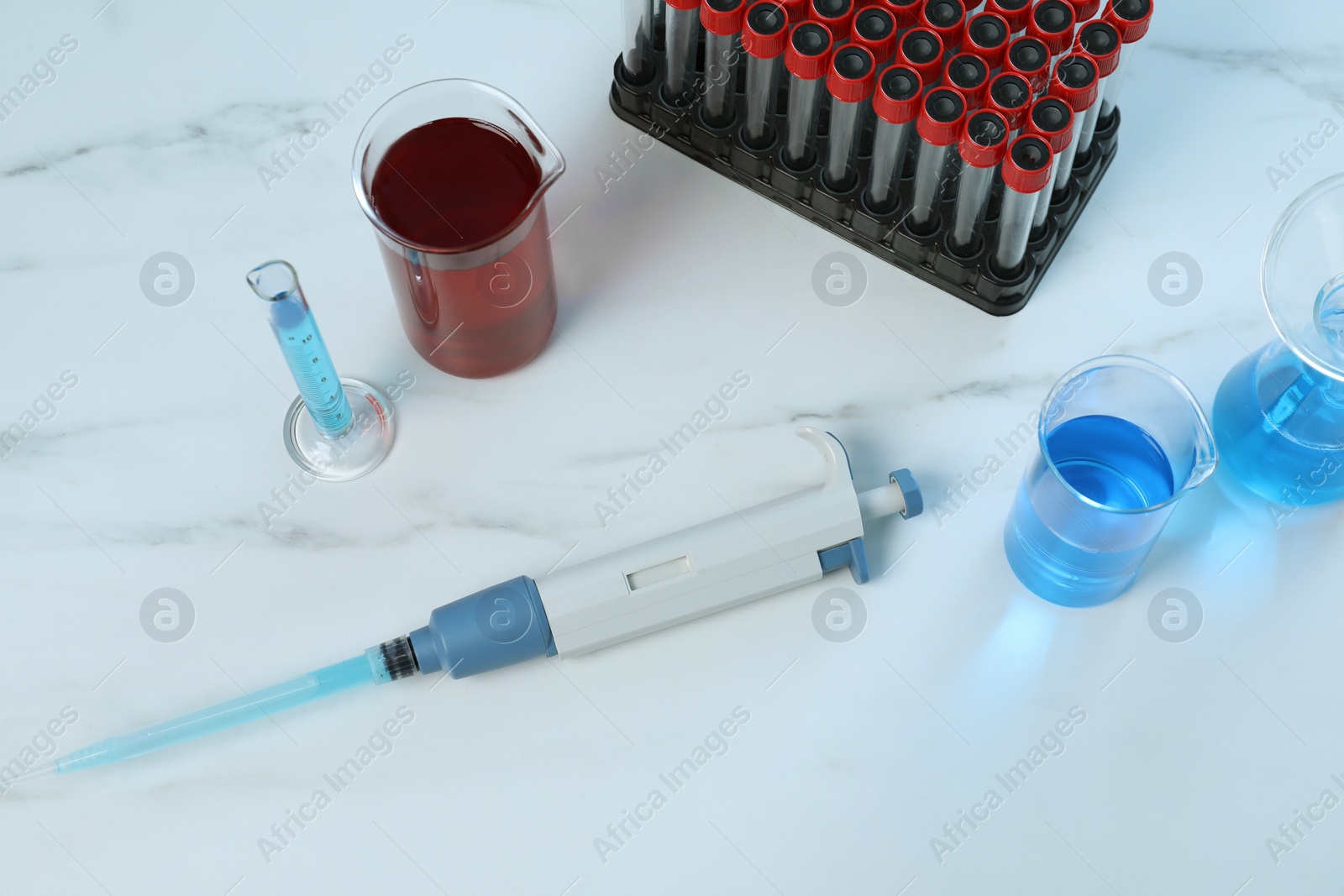 Photo of Laboratory analysis. Micropipette and different glassware on white marble table, above view