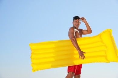 Photo of Man with yellow inflatable mattress against blue sky