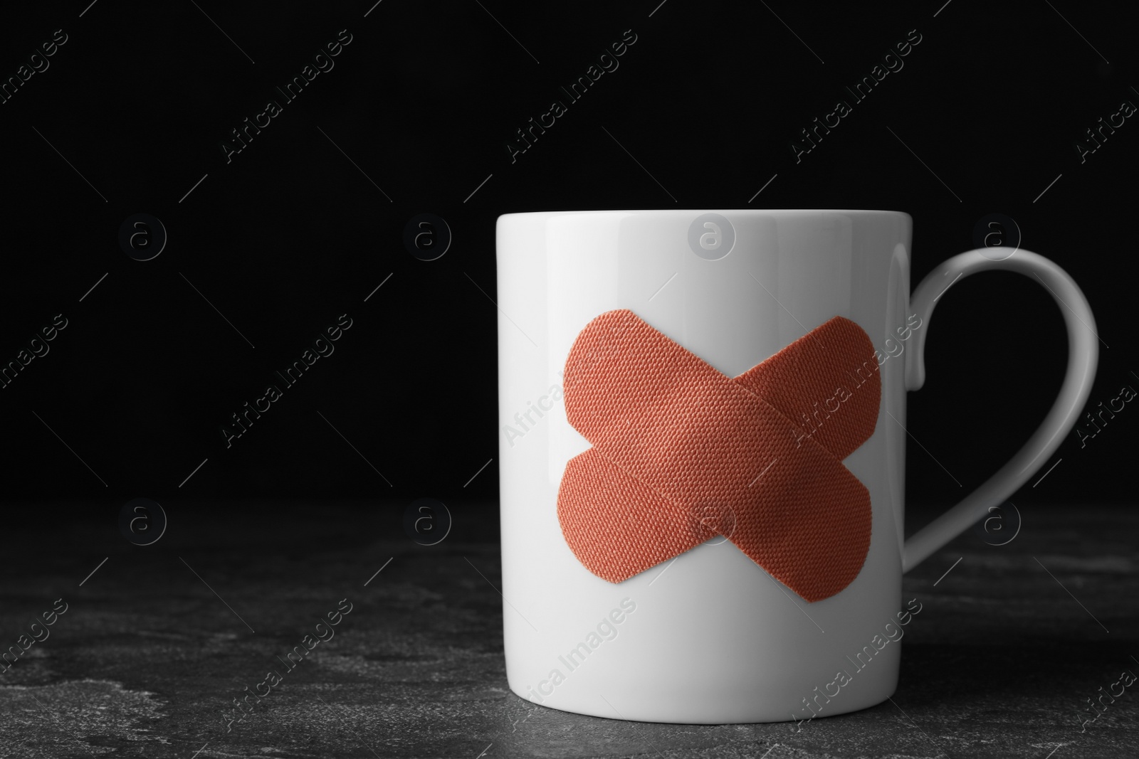 Photo of Cup with sticking plasters on grey stone table