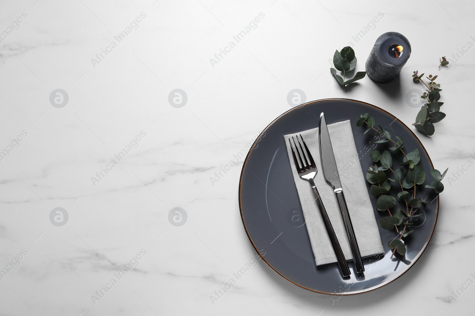 Photo of Stylish setting with cutlery and eucalyptus leaves on white marble table, flat lay. Space for text