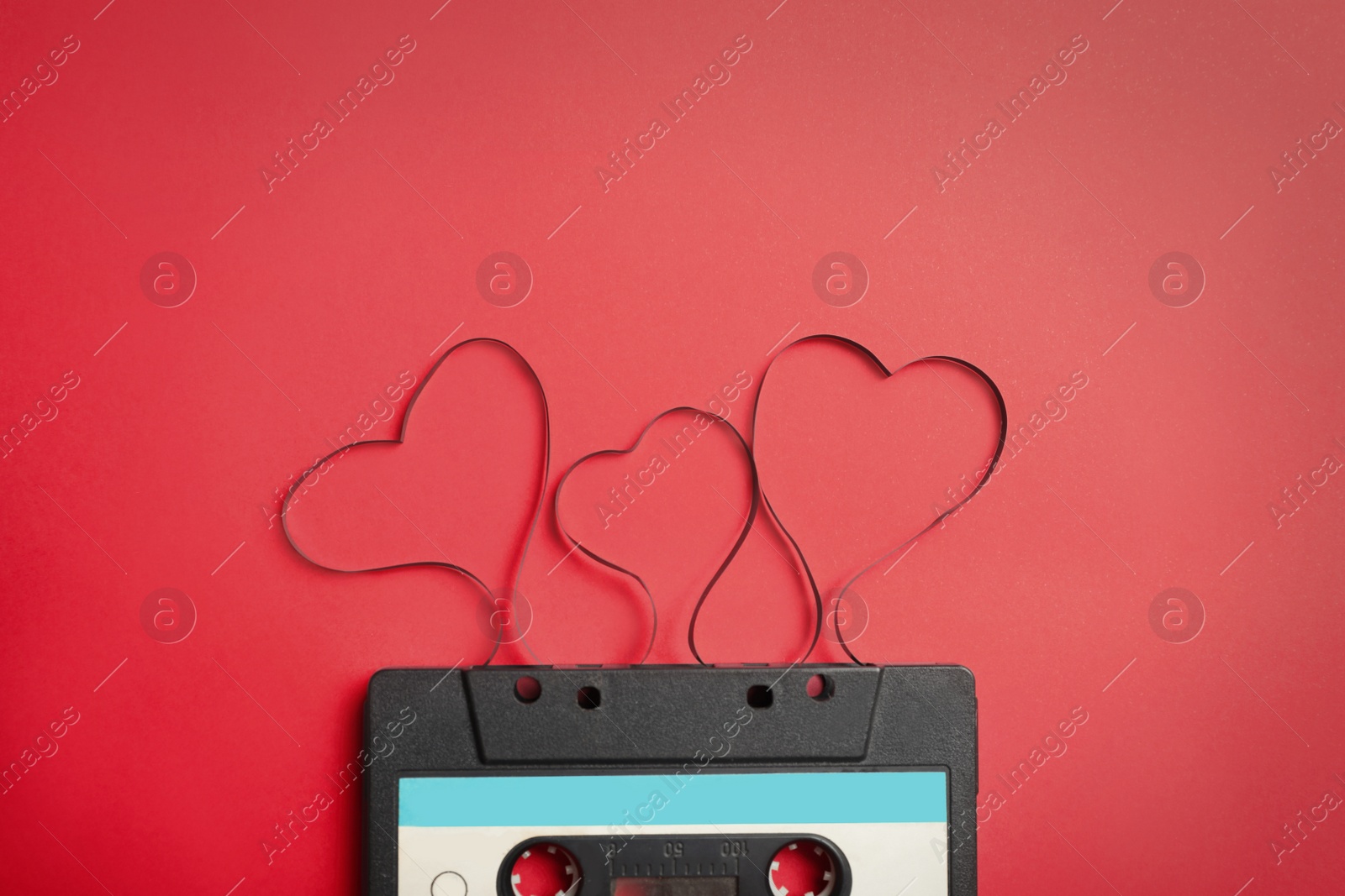 Photo of Music cassette and hearts made with tape on red background, top view. Listening love song